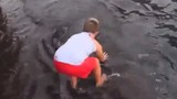 Bé trai thản nhiên chơi đùa với cá đuối trước biển